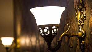 Une lampe murale dotée d’un abat-jour blanc et d’un motif décoratif découpé.