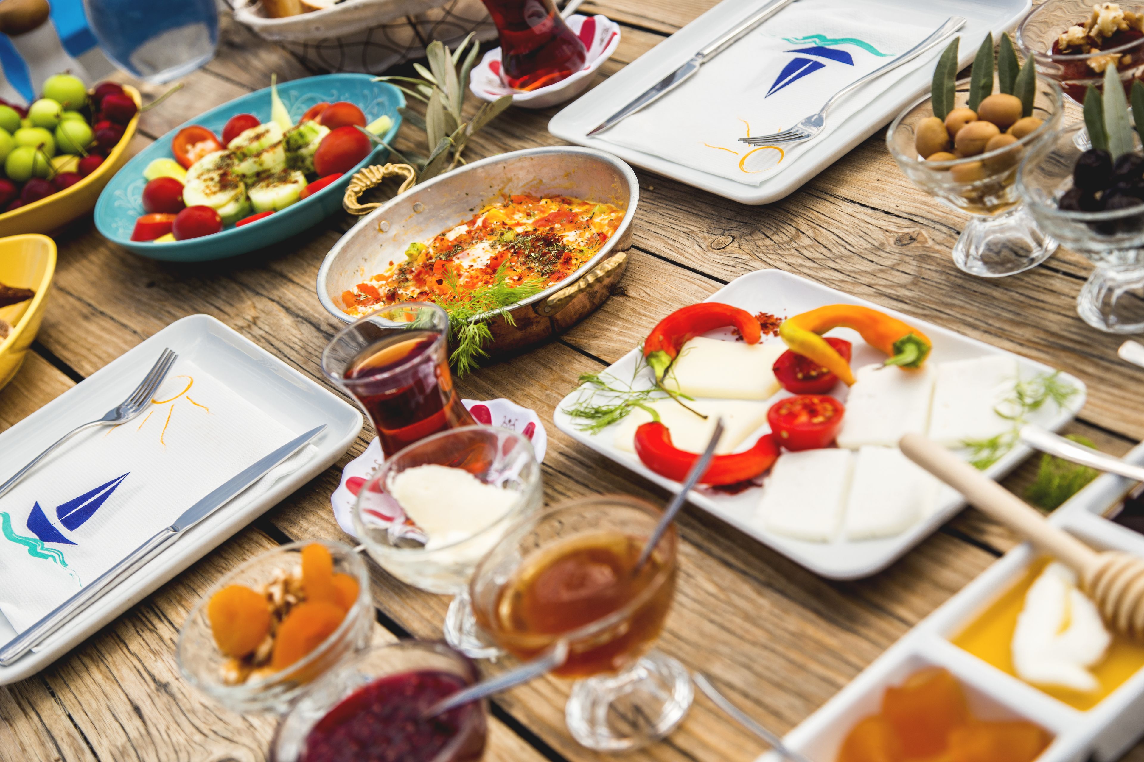 Una mesa de madera con diferentes platos y utensilios, incluyendo platos con comida, tazones y vasos.