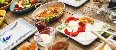 Una mesa de madera con diferentes platos y utensilios, incluyendo platos con comida, tazones y vasos.