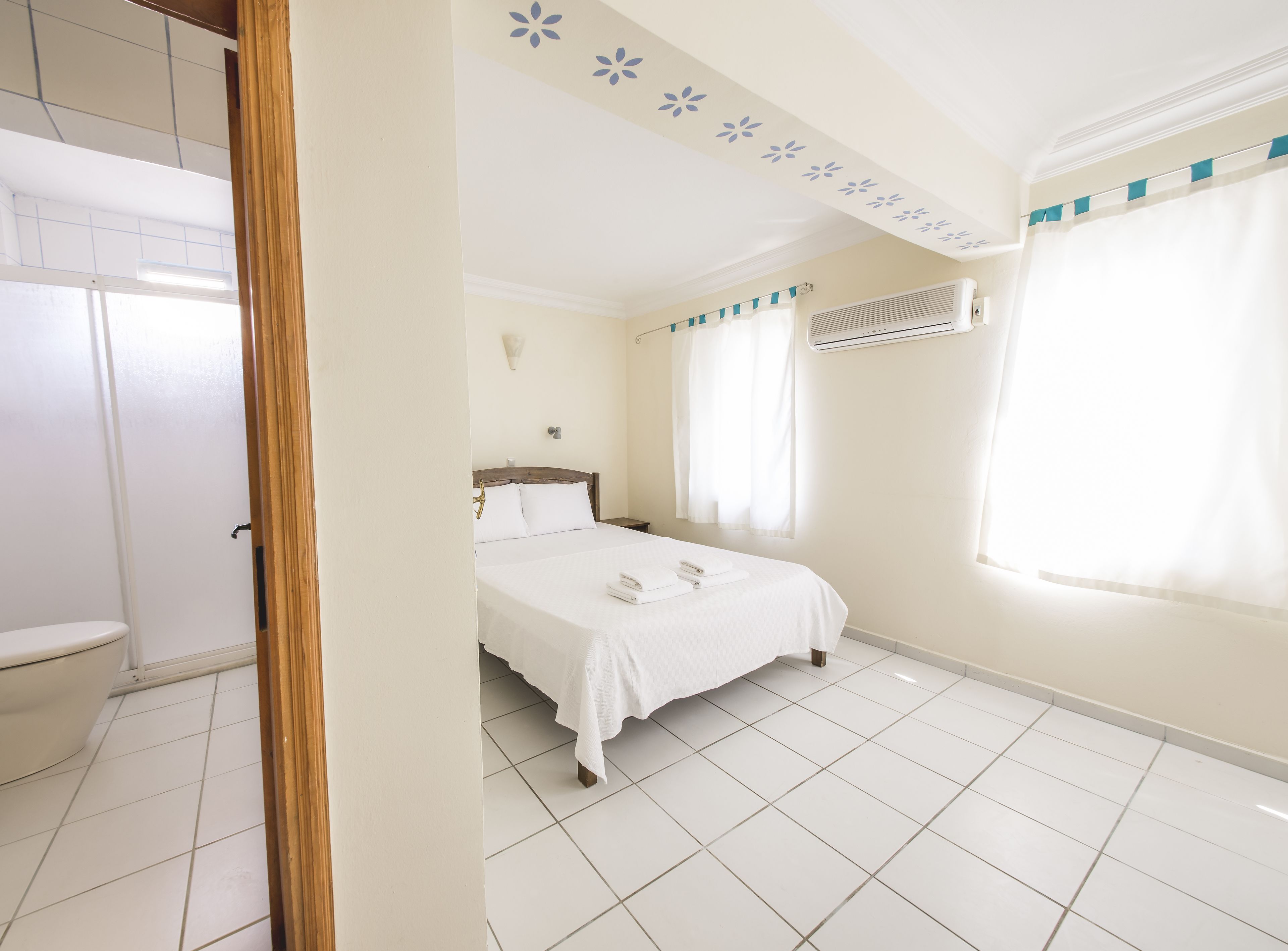 A hotel room with a bed, a toilet, and a shower area.