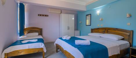 A hotel room with two wooden beds, a wardrobe, and a mirror on the wall.