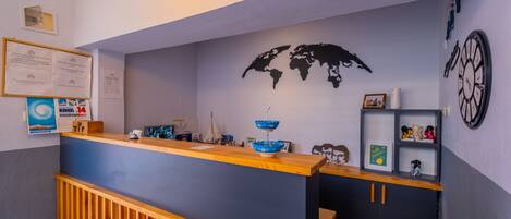 A reception desk with a world map, framed documents, and a clock on the wall.