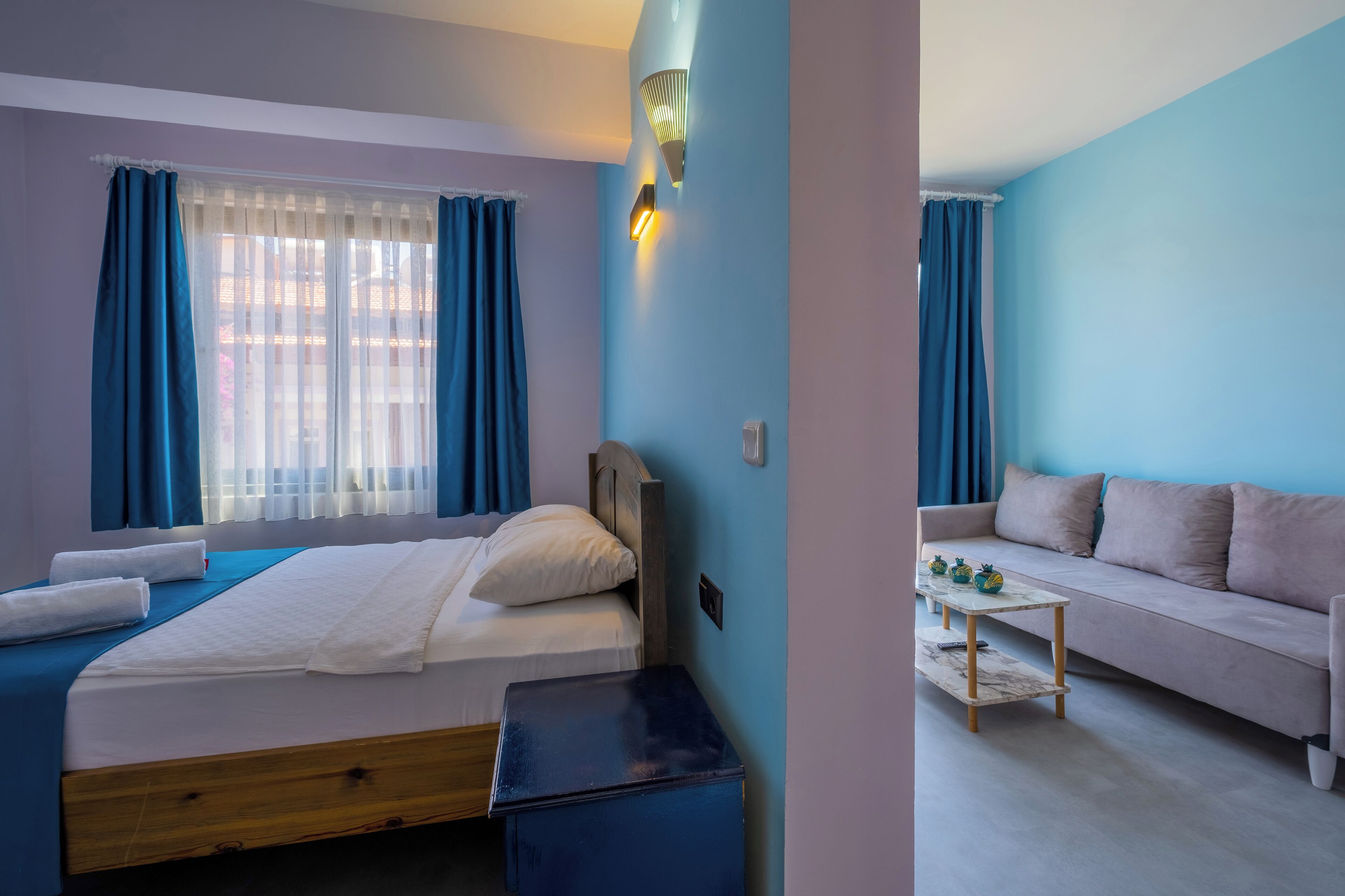 Un dormitorio con cama, mesita de noche y ventana con cortinas.