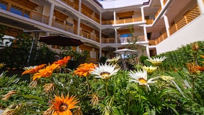 A multi-story hotel with balconies and a garden area with flowers. - Hotel Ladakh Inn (Leh)