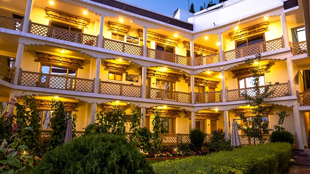 A multi-story hotel with balconies, a garden, and a well-lit facade. - Hotel Ladakh Inn (Leh)