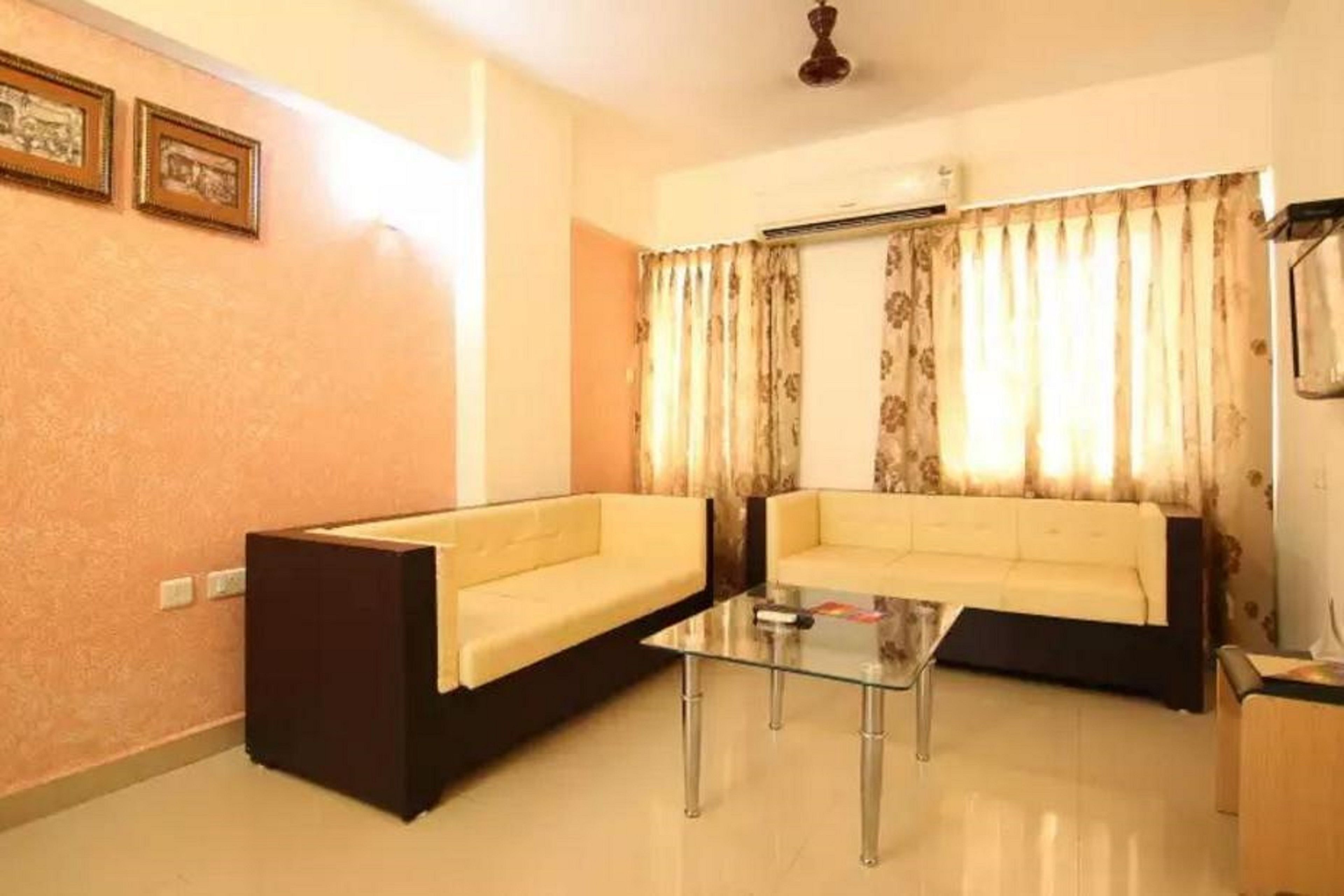 A living room with two sofas, a glass coffee table, and a ceiling fan.