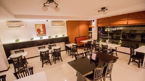 Un restaurant doté de nombreuses tables et chaises, de systèmes de climatisation et d’un mur décoratif.