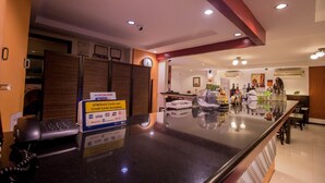 Un espace d’accueil d’hôtel comprenant un comptoir, un téléphone et un panneau indiquant les modes de paiement acceptés.