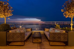 Une terrasse sur le toit, avec deux canapés, une table basse et une vue sur un pont au crépuscule.