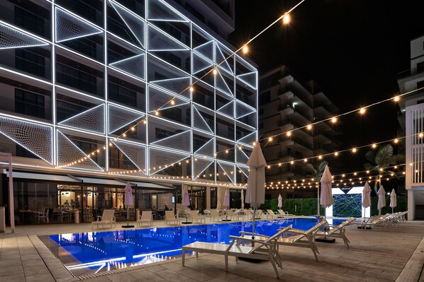 A modern hotel with a pool area, outdoor seating, and string lights. - Nyota Hotel & Conference Center (Constanta)