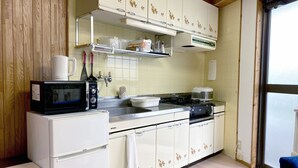 Ett kompakt kök med vita skåp, en mikrovågsugn, en spis och en kaffebryggare.