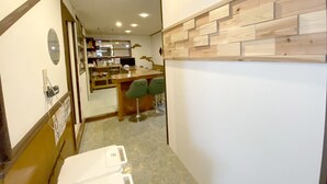 En smal hall med en träpanel på väggen, ett litet köksutrymme och en sittgrupp med två stolar.