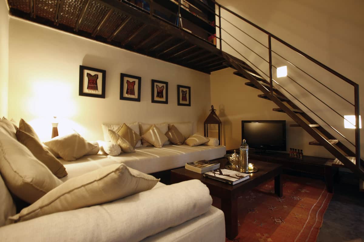 A living room with a sofa, a coffee table, a television, and a staircase.