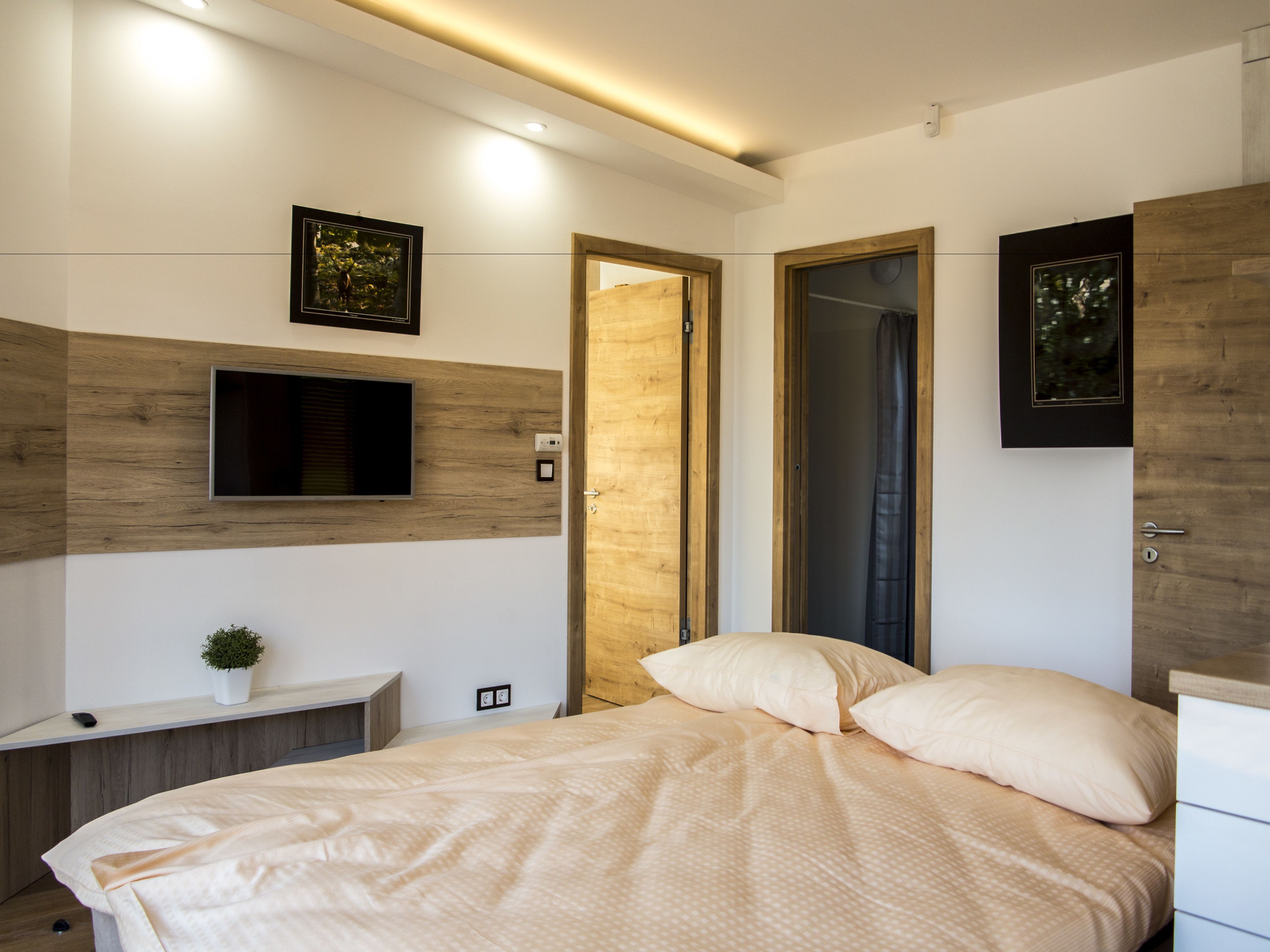 Un dormitorio moderno con una cama, un televisor montado en la pared y una puerta de madera.