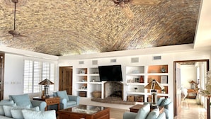 Un salon spacieux doté d’une cheminée, de sièges confortables et d’un ventilateur de plafond.