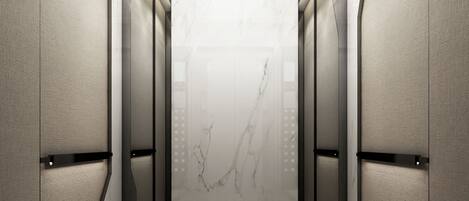 A modern elevator with a marble wall, metallic handrails, and a ceiling with recessed lighting.