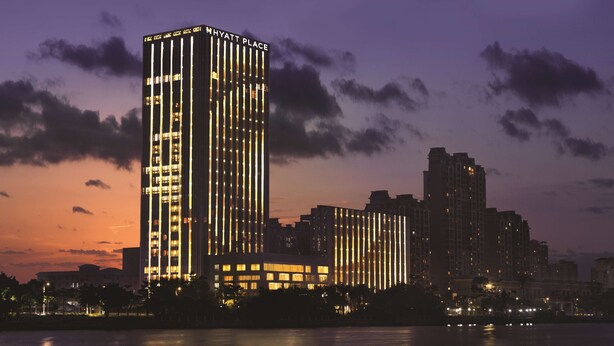 Un hotel de gran altura con líneas verticales iluminadas, vista al frente marítimo y el perfil urbano al fondo.