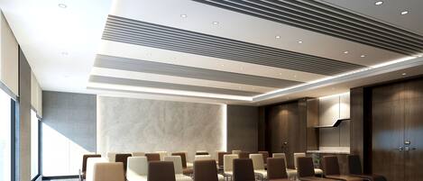 A conference room with rows of chairs, a patterned carpet, and a modern ceiling design.