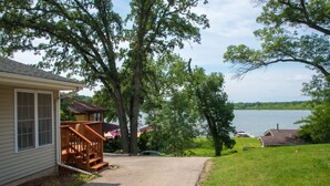 A house with a porch, a gravel driveway, and a view of a lake.