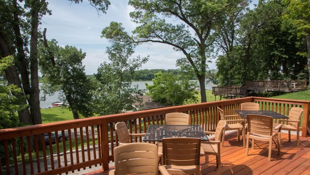 A deck with outdoor furniture overlooking a lake.