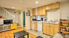 Cozy living space with a kitchenette, flat-screen TV, and wooden staircase.