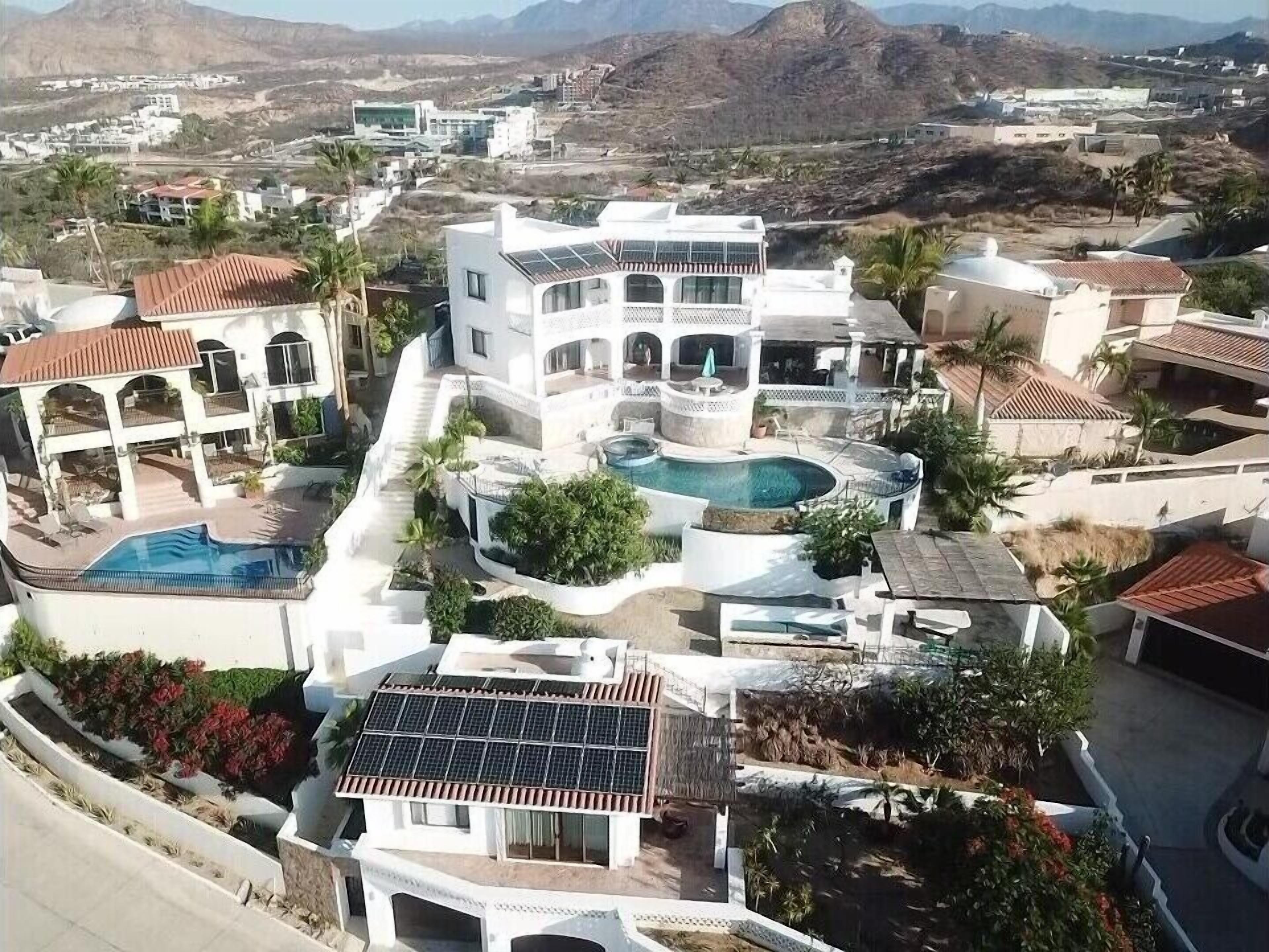 A modern residential area with multiple houses, a central swimming pool, and solar panels.