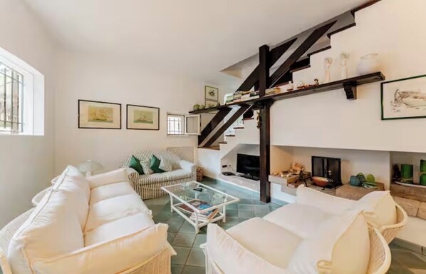 Una sala de estar amplia con techo alto, chimenea y una escalera que conduce a un nivel superior.