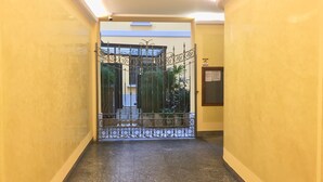 A hallway with a metal gate leading to a balcony with plants.