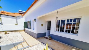 A building with a white exterior, a tiled roof, and a small garden area with pebbles and a potted plant. - Casa da Achada in Arco da Calheta (Arco da Calheta)