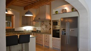 A kitchen with a central island, bar stools, a stainless steel refrigerator, and a microwave. - Provencal country house with heated freeform pool (Châteaurenard)