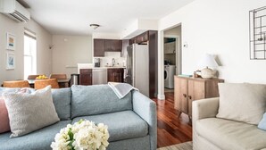 A modern living room with a grey sofa, a beige armchair, and a wooden cabinet. - Top-Floor 1-Bedroom Condo in Downtown Traverse City – Walk to Beaches & Dining (Traverse City)