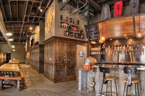 Zona de bar con mobiliario de madera, barra y varios grifos de cerveza.