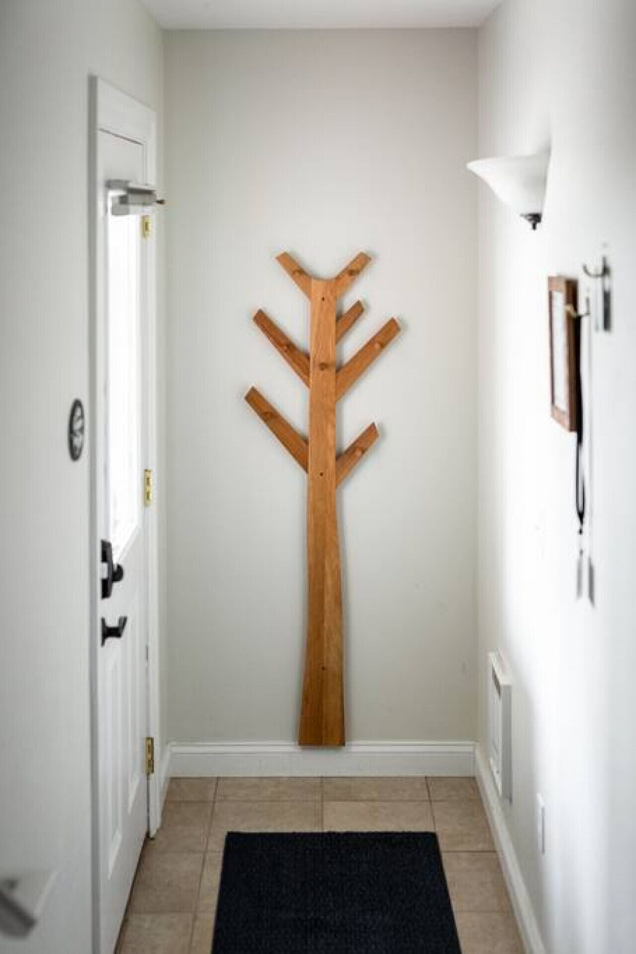 A hallway with a wooden coat rack and a door on the left.