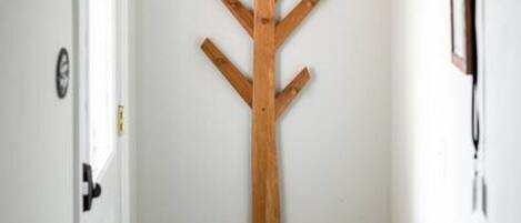 A hallway with a wooden coat rack and a door on the left.