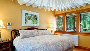 Ein Schlafzimmer mit einem großen Bett, einer Holzkommode, einem Nachttisch, einer Lampe und einem gerahmten Bild an der Wand.