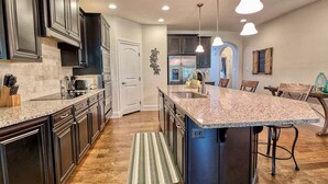 A modern kitchen with dark cabinets, granite countertops, and a central island.
