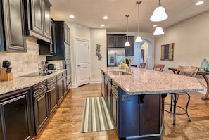 A modern kitchen with dark cabinets, granite countertops, and a central island.
