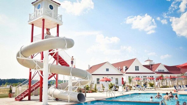A water park with a large pool, a water slide, and a lifeguard tower.