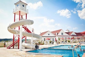 Um parque aquático com uma piscina grande, um toboágua e uma torre de salva-vidas.