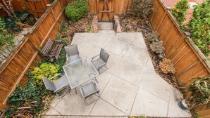 A backyard patio with a table and chairs, surrounded by a wooden fence and various plants. - RETREAT on the CREEK - Businees Travelor or Weekend Getaway. HISTORIC DISTRICT. (Frederick)