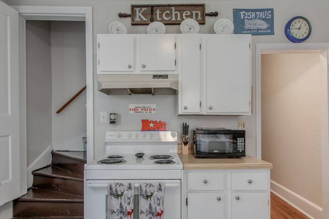 Una cocina compacta con gabinetes blancos, estufa, microondas y un letrero que dice "FIRE POLICE".