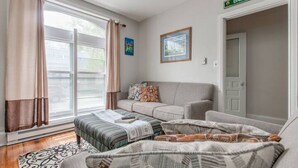 A cozy living room with a sofa, a patterned rug, and a large window with curtains. - RETREAT on the CREEK - Businees Travelor or Weekend Getaway. HISTORIC DISTRICT. (Frederick)