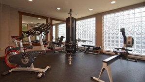 Ein Fitnessstudio mit Laufbändern, Krafttrainingsgeräten und großen Fenstern.