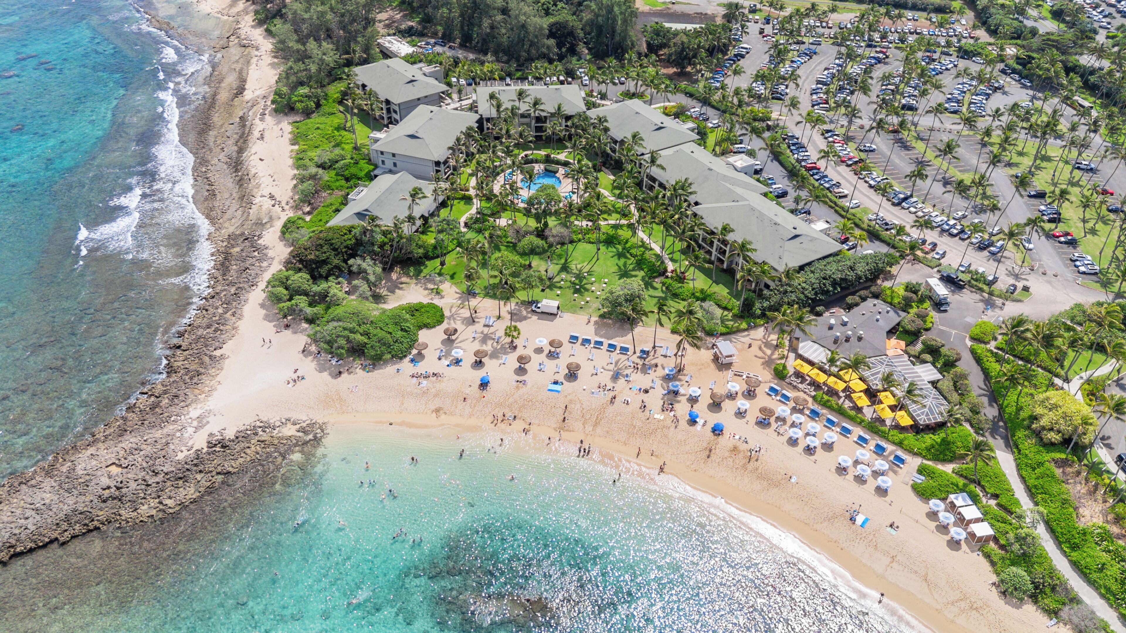 An aerial view of a resort with a beachfront, a pool area, and multiple buildings.
