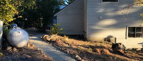 A house with a gravel driveway, a large water tank, and a wooden stump.