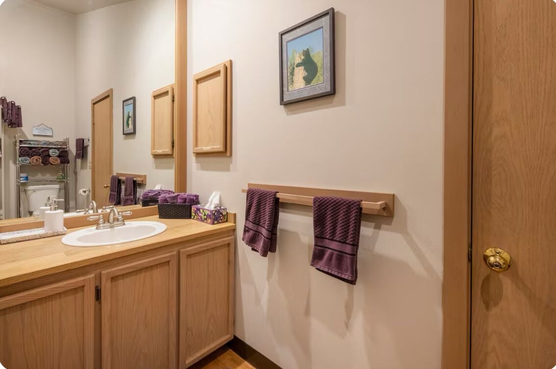 A bathroom with wooden cabinets, a sink, a towel rack, and a framed picture on the wall.