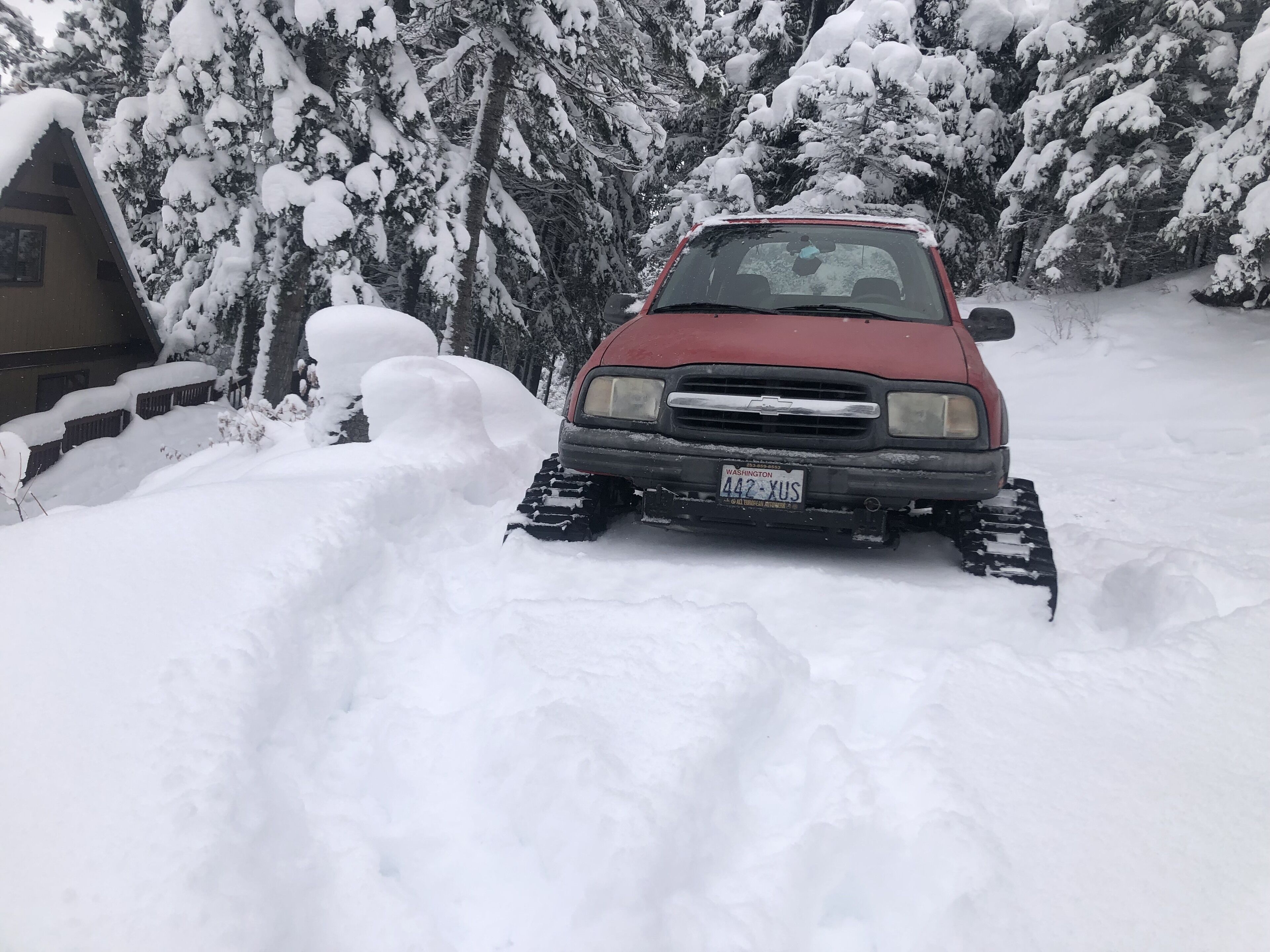 A red vehicle with snow tracks in a snowy landscape.