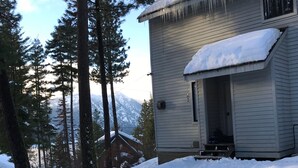 A snowmobile parked in front of a house with a snow-covered roof and icicles.