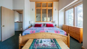 A bedroom with a wooden bed, a large window, and a dresser.