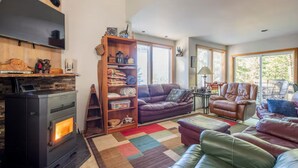 A cozy living room with a fireplace, leather sofas, a coffee table, and a bookshelf.